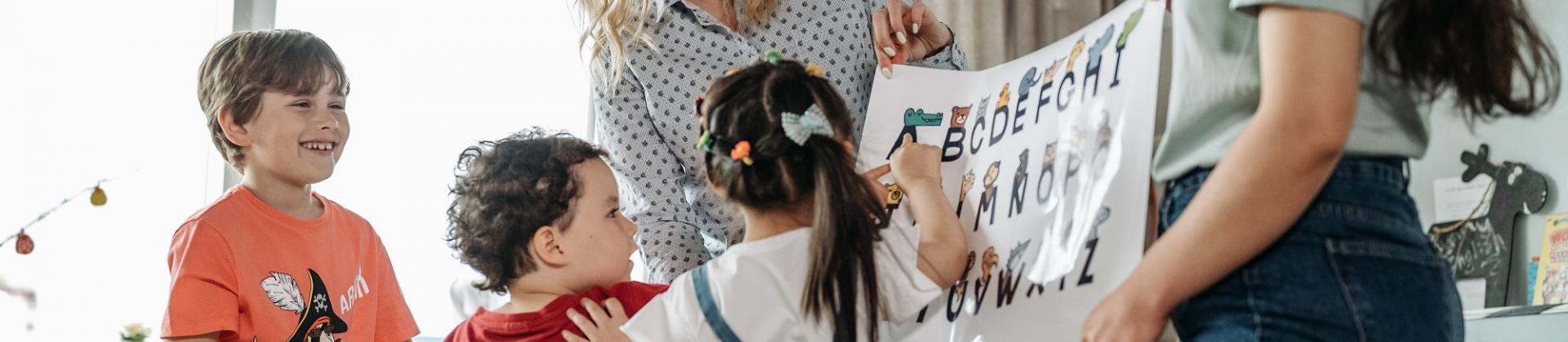 Lehrerinnen zeigen Schülern ein Plakat