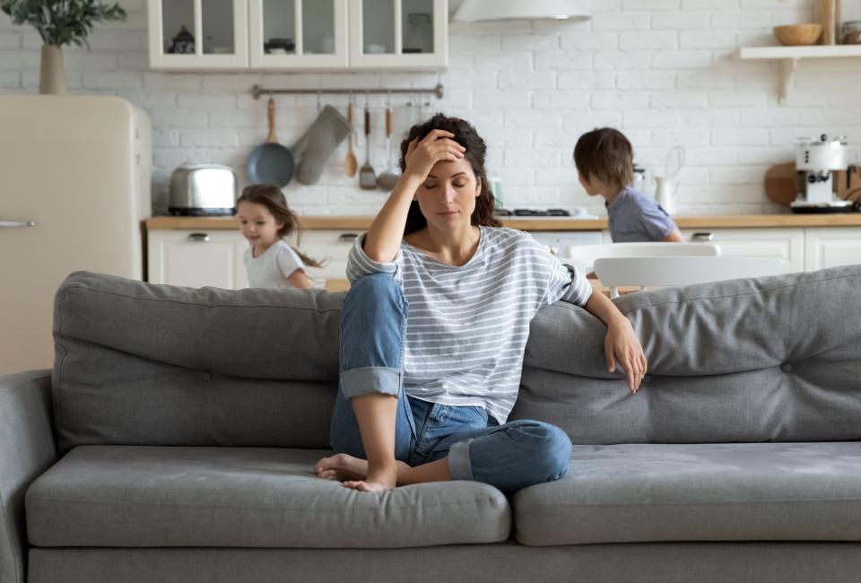 Erschöpfte Mutter sitzt auf dem Sofa im Wohnzimmer