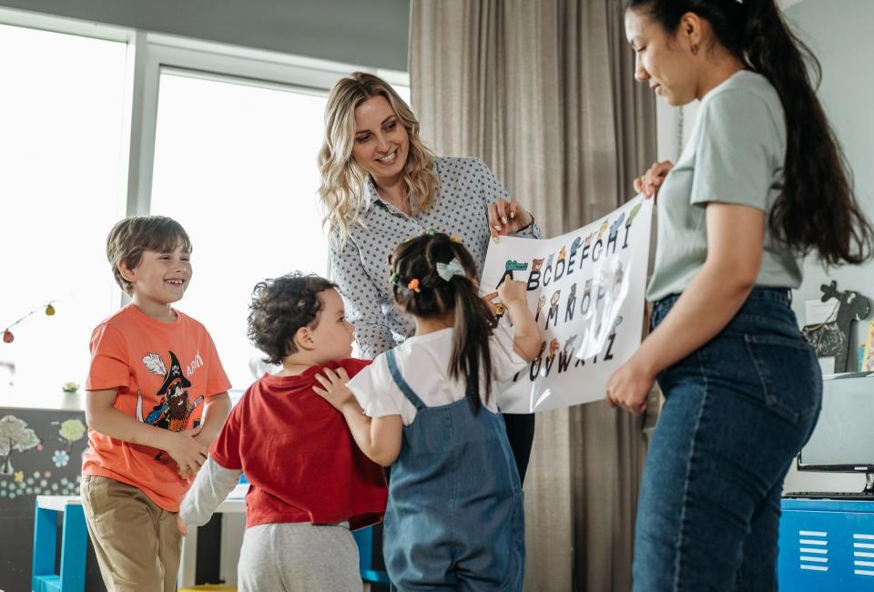 Lehrerinnen zeigen Schülern ein Plakat